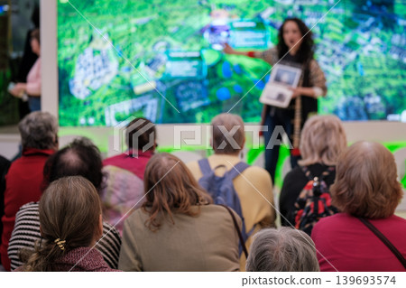 Presenter giving urban planning presentation to senior audience at interactive map display in exhibition hall Presenter giving urban planning presentation to senior audience at interactive map display in exhibition hall 139693574