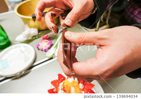 The process of decorating a cake with chocolate by hand. 139694034