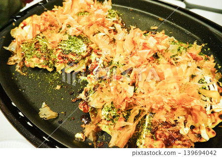 Sprinkle bonito flakes on the okonomiyaki once it's cooked. 139694042