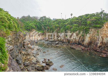 海灣中寧靜的岩石海岸線,四周綠樹環繞。 海灣中寧靜的岩石海岸線,四周綠樹環繞。 139694094