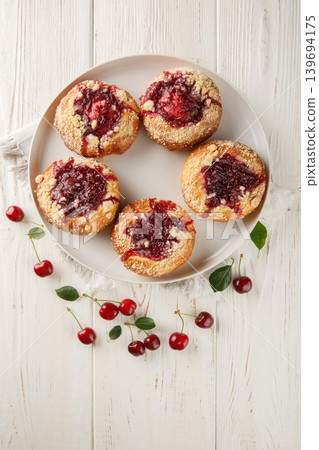 Close-up of open buns with cherry jam filling and streusel in a plate on a wooden table. Vertical top view Close-up of open buns with cherry jam filling and streusel in a plate on a wooden table. Vertical top view 139694175