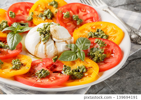 Caprese salad with burrata, tomatoes, basil pesto and balsamic vinegar close-up in a plate. Horizontal Caprese salad with burrata, tomatoes, basil pesto and balsamic vinegar close-up in a plate. Horizontal 139694191