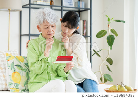 一位年長的母親和她中年的女兒正在看存摺。 139694382