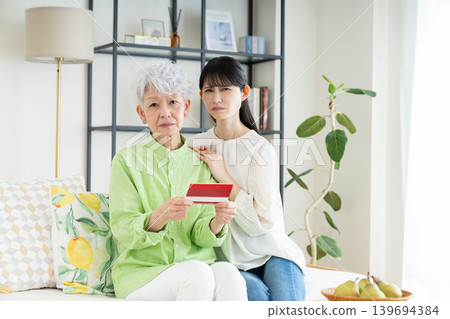 一位年長的母親和她中年的女兒正在看存摺。 一位年長的母親和她中年的女兒正在看存摺。 139694384