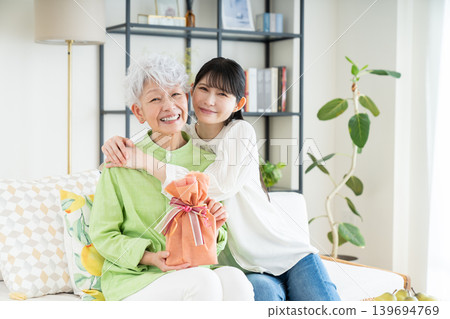 A middle-aged daughter gives a gift to her senior mother. A middle-aged daughter gives a gift to her senior mother. 139694769