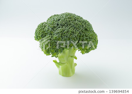 A photograph of broccoli standing upright against a white background, taken from a diagonal angle above. A photograph of broccoli standing upright against a white background, taken from a diagonal angle above. 139694854
