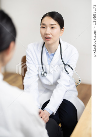 一位身穿白大褂的日本女醫生握著病人的手，微笑著鼓勵他們。 139695172
