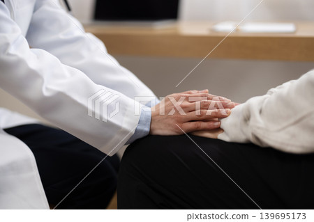 特寫鏡頭拍攝一位身穿白大褂的女醫生握著病人的手。 139695173