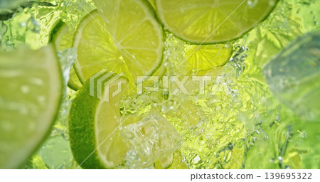 Fresh lime slices falling into sparkling water with bubbles and splashes. Bright green citrus macro photo, perfect for beverage, freshness, summer, cocktail and healthy lifestyle visuals. Fresh lime slices falling into sparkling water with bubbles and splashes. Bright green citrus macro photo, perfect for beverage, freshness, summer, cocktail and healthy lifestyle visuals. 139695322