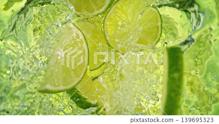 Fresh lime slices falling into sparkling water with bubbles and splashes. Bright green citrus macro photo, perfect for beverage, freshness, summer, cocktail and healthy lifestyle visuals. Fresh lime slices falling into sparkling water with bubbles and splashes. Bright green citrus macro photo, perfect for beverage, freshness, summer, cocktail and healthy lifestyle visuals. 139695323