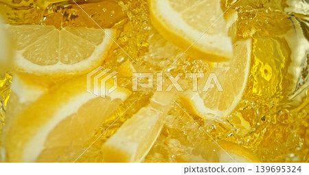 Fresh lemon slices falling into sparkling water with bubbles and splashes. Bright yellow citrus macro photo, perfect for beverage, freshness, summer, cocktail and healthy lifestyle visuals. 139695324