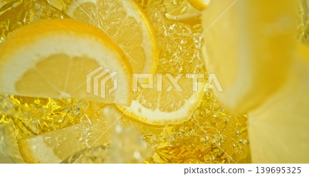 Fresh lemon slices falling into sparkling water with bubbles and splashes. Bright yellow citrus macro photo, perfect for beverage, freshness, summer, cocktail and healthy lifestyle visuals. 139695325