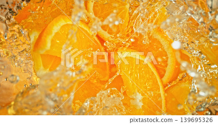 Fresh orange slices falling into sparkling water with bubbles and splashes. Vibrant citrus macro photo, perfect for beverage, freshness, summer, cocktail and healthy lifestyle visuals. 139695326
