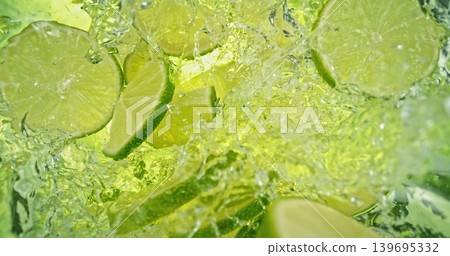 Fresh lime slices falling into sparkling water with bubbles and splashes. Bright green citrus macro photo, perfect for beverage, freshness, summer, cocktail and healthy lifestyle visuals. Fresh lime slices falling into sparkling water with bubbles and splashes. Bright green citrus macro photo, perfect for beverage, freshness, summer, cocktail and healthy lifestyle visuals. 139695332