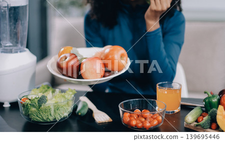 Young nutritionist showing bell peppers during an online video call consulting about healthy eating, sitting at home at a table with vegetables, laptop and measuring tape Young nutritionist showing bell peppers during an online video call consulting about healthy eating, sitting at home at a table with vegetables, laptop and measuring tape 139695446