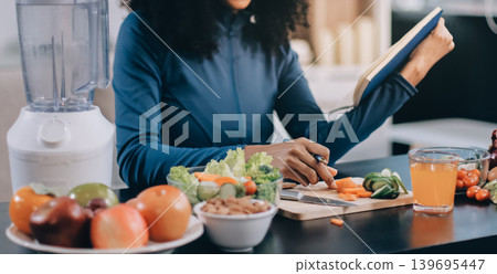 Young nutritionist showing bell peppers during an online video call consulting about healthy eating, sitting at home at a table with vegetables, laptop and measuring tape Young nutritionist showing bell peppers during an online video call consulting about healthy eating, sitting at home at a table with vegetables, laptop and measuring tape 139695447