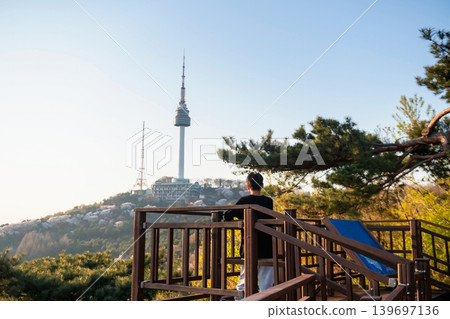 Korean young man view Seoul tower with cherry blossom at sunset Korean young man view Seoul tower with cherry blossom at sunset 139697136