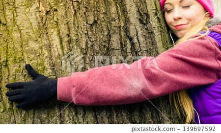 Woman wearing sportswear hugging tree Woman wearing sportswear hugging tree 139697592