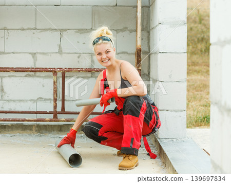 Woman carrying pipes on construction site 139697834