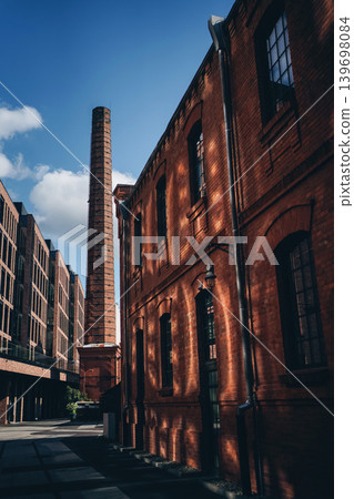 historic industrial brick building with tall chimney and modern urban loft architecture, renovated red brick warehouse facade with factory chimney in contemporary city district, Warsaw Poland historic industrial brick building with tall chimney and modern urban loft architecture, renovated red brick warehouse facade with factory chimney in contemporary city district, Warsaw Poland 139698084