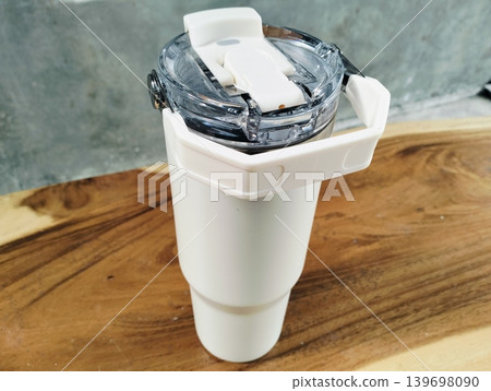 White Stainless Steel Tumbler with Silver Handle on Wooden Table White Stainless Steel Tumbler with Silver Handle on Wooden Table 139698090