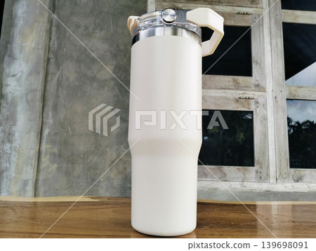 White Stainless Steel Tumbler with Silver Handle on Wooden Table White Stainless Steel Tumbler with Silver Handle on Wooden Table 139698091