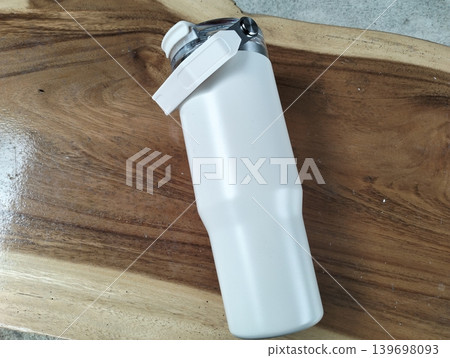 White Stainless Steel Tumbler with Silver Handle on Wooden Table White Stainless Steel Tumbler with Silver Handle on Wooden Table 139698093