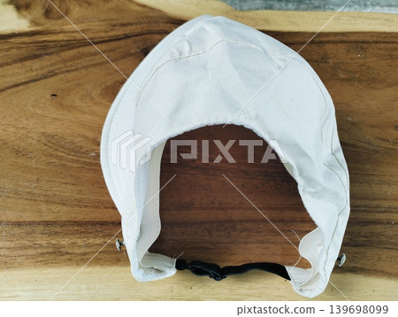 Mockup of a plain white bucket hat on a wooden table outdoors Mockup of a plain white bucket hat on a wooden table outdoors 139698099