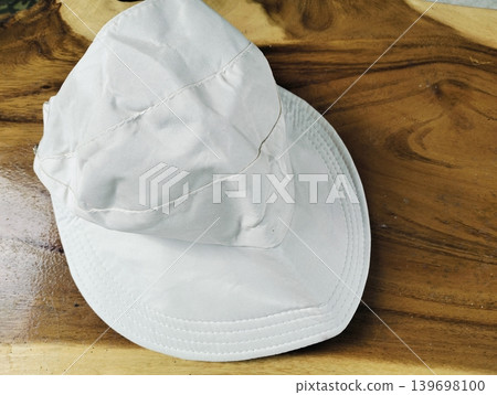 Mockup of a plain white bucket hat on a wooden table outdoors Mockup of a plain white bucket hat on a wooden table outdoors 139698100