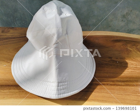 Mockup of a plain white bucket hat on a wooden table outdoors 139698101