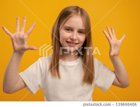 Cute Little Girl Smiles, Showing Open Palms, On An Orange Background Cute Little Girl Smiles, Showing Open Palms, On An Orange Background 139698406