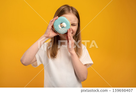 Cute Little Girl Smiles Looking Through A Donut Hole Against An Orange Background Cute Little Girl Smiles Looking Through A Donut Hole Against An Orange Background 139698407