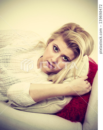 Woman lying on couch feeling very unwell Woman lying on couch feeling very unwell 139698472