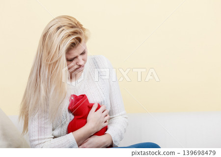 Woman feeling stomach cramps sitting on cofa Woman feeling stomach cramps sitting on cofa 139698479