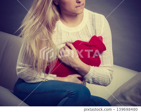 Woman feeling stomach cramps sitting on cofa Woman feeling stomach cramps sitting on cofa 139698480