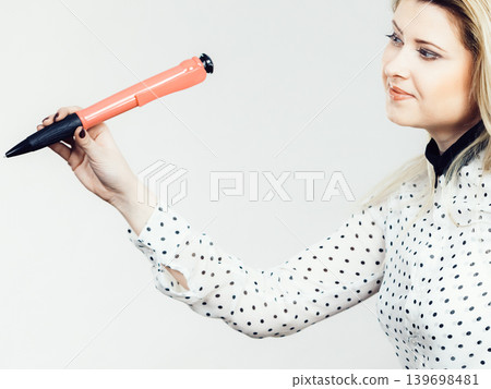 Woman holding big oversized pen Woman holding big oversized pen 139698481