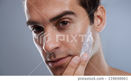 Portrait, cream and man with skincare, dermatology or wellness on grey studio background. Portrait, person or model with grooming routine or treatment with lotion or moisture with glow or smooth skin Portrait, cream and man with skincare, dermatology or wellness on grey studio background. Portrait, person or model with grooming routine or treatment with lotion or moisture with glow or smooth skin 139698661