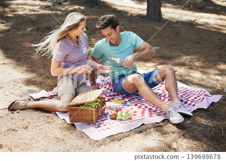 Couple, wine glass and picnic outdoor in nature or park for celebration of love, holiday date and valentines day. Young people with fruits basket, drinks or champagne bottle in forest on anniversary 139698678