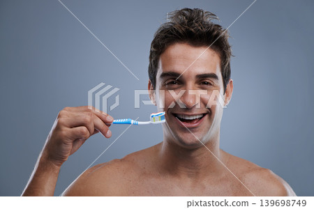 Portrait, man or wellness with toothbrush, oral hygiene or body care on grey studio background. Face, person or model with fresh breath or health with toothpaste or morning routine with dental smile Portrait, man or wellness with toothbrush, oral hygiene or body care on grey studio background. Face, person or model with fresh breath or health with toothpaste or morning routine with dental smile 139698749