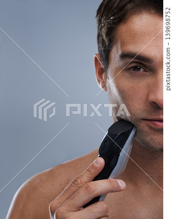 Man, electric shaver and face with closeup studio portrait, grooming and skincare by grey background. Person, model and shaving beard with hygiene, facial hair removal or mockup for cosmetic change Man, electric shaver and face with closeup studio portrait, grooming and skincare by grey background. Person, model and shaving beard with hygiene, facial hair removal or mockup for cosmetic change 139698752