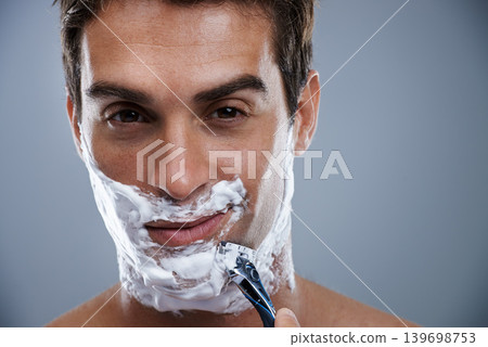Man, razor and shaving in studio closeup for grooming, skincare and beard in portrait by grey background. Person, model and self care with cream, facial hair removal and product for cosmetic change Man, razor and shaving in studio closeup for grooming, skincare and beard in portrait by grey background. Person, model and self care with cream, facial hair removal and product for cosmetic change 139698753