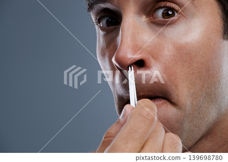 Man, nose and hair with tweezers in studio on grey background for self care, wellness or dermatology. Male person, face and grooming for cosmetic beauty or healthy cleaning, wellbeing or mockup space Man, nose and hair with tweezers in studio on grey background for self care, wellness or dermatology. Male person, face and grooming for cosmetic beauty or healthy cleaning, wellbeing or mockup space 139698780