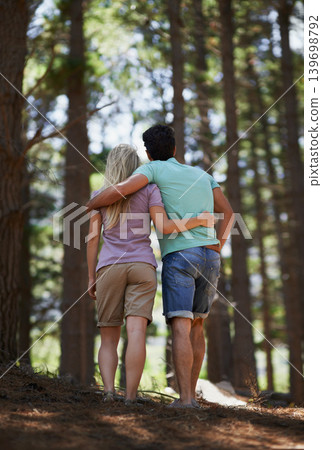 Couple, walking and hug in forest for love, embrace or support in trust, care or bonding in nature. Rear view or back of young man and woman in romance, affection or hiking together in outdoor woods Couple, walking and hug in forest for love, embrace or support in trust, care or bonding in nature. Rear view or back of young man and woman in romance, affection or hiking together in outdoor woods 139698792