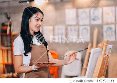 Female artist wears black hat posing near picture indoor the studio Female artist wears black hat posing near picture indoor the studio 139698833