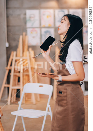 Female artist wears black hat posing near picture indoor the studio Female artist wears black hat posing near picture indoor the studio 139698834