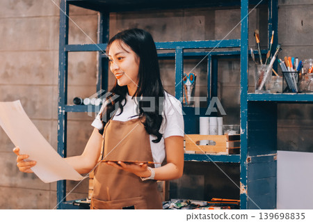Female artist wears black hat posing near picture indoor the studio 139698835