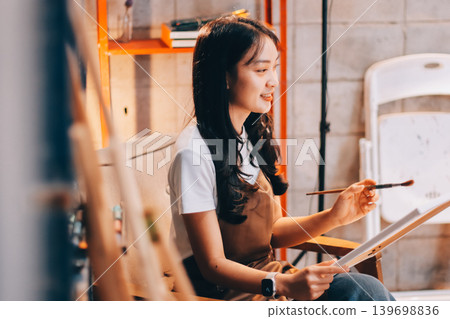 Female artist wears black hat posing near picture indoor the studio Female artist wears black hat posing near picture indoor the studio 139698836