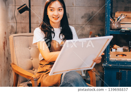 Female artist wears black hat posing near picture indoor the studio Female artist wears black hat posing near picture indoor the studio 139698837