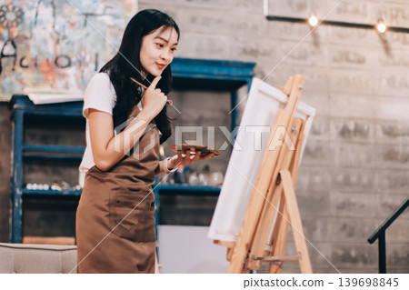 Female artist wears black hat posing near picture indoor the studio 139698845