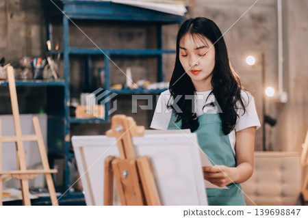 Female artist wears black hat posing near picture indoor the studio Female artist wears black hat posing near picture indoor the studio 139698847
